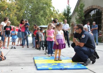 Turlock Firefighters teaching children how to stop, drop, and roll if their clothes were to catch on fire as a way to estinguish the fire.