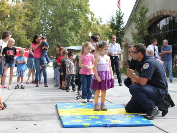 Turlock Firefighters teaching children how to stop, drop, and roll if their clothes were to catch on fire as a way to estinguish the fire.
